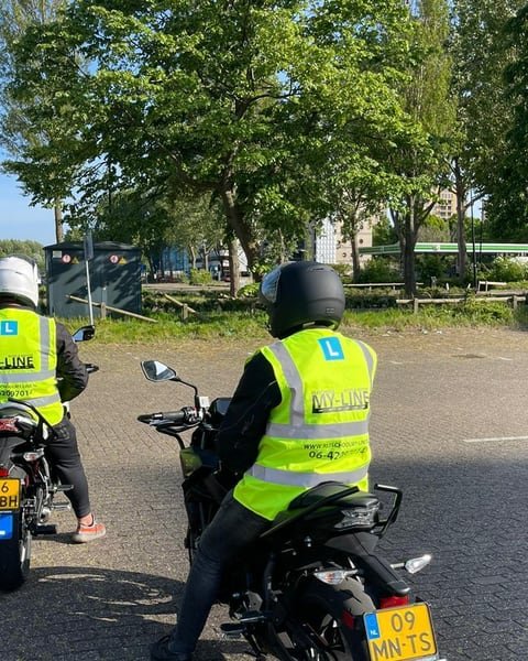 Twee motorleerlingen van MY-Line met hesje en helm op de lesmotor