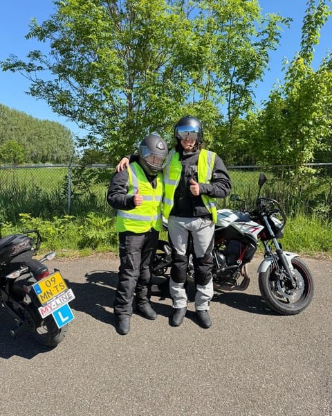 Twee motorrijders met helm en geel hesje naast de lesmotor van MY-Line
