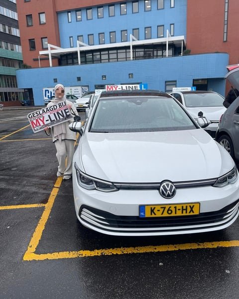 De witte Volkswagen Golf van MY-Line recht van voren met het dakbord