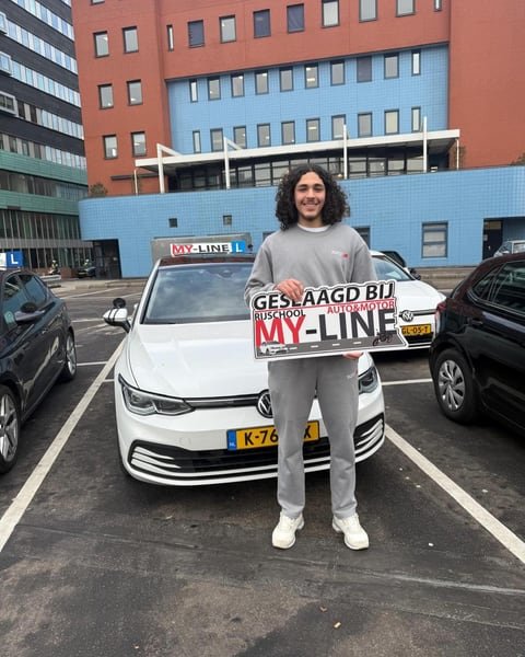 Geslaagde leerling met het bord van MY-Line voor de lesauto