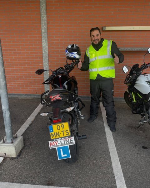 Motorleerling met geel hesje naast de lesmotor van MY-Line met het L-bord