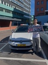 Geslaagde leerling met het bord van MY-Line bij de lesauto of lesmotor