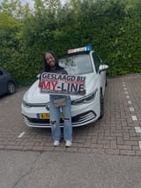Geslaagde leerling met het bord van MY-Line bij de lesauto of lesmotor