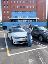 Geslaagde leerling met het bord van MY-Line bij de lesauto of lesmotor